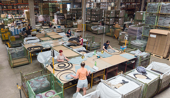 Mitarbeiter bei der Vorverpackung an mehreren Arbeitstischen in der Lagerhalle.