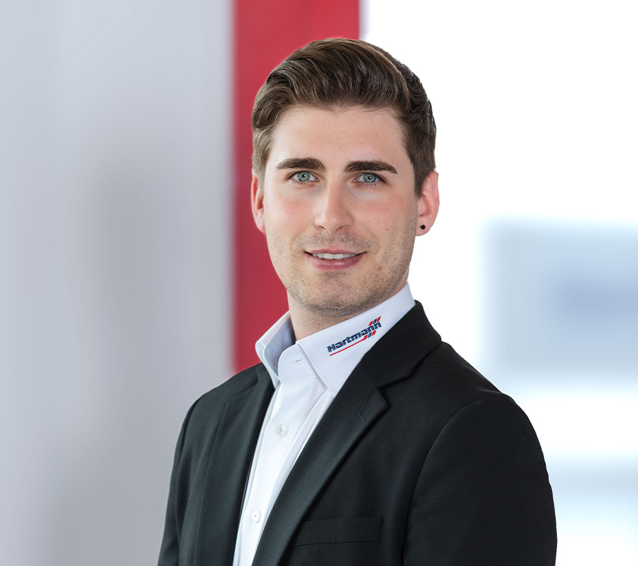 Mitarbeiter von Hartmann im Business-Outfit mit Hartmann-Logo am Hemdkragen.