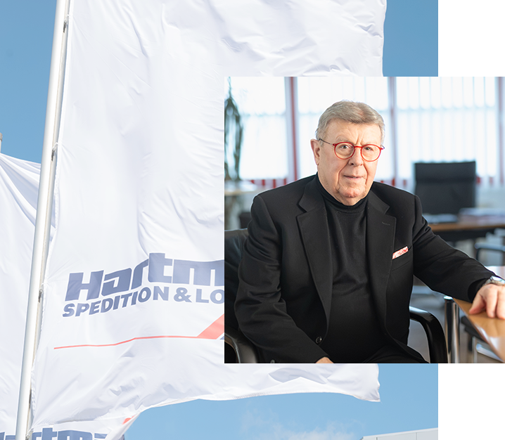 Porträt eines Geschäftsführers von Hartmann Spedition & Logistik vor Firmenflagge