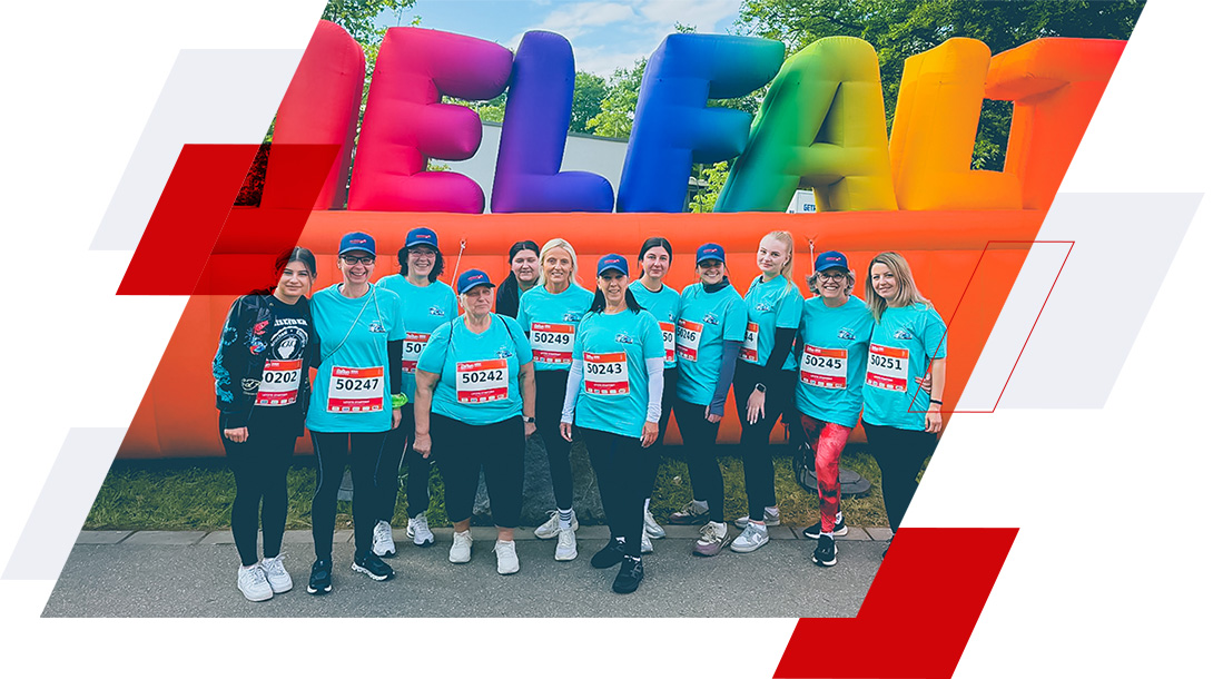 Hartmann-Laufteam beim B2Run Firmenlauf in Karlsruhe in türkisfarbenen Laufshirts vor dem bunten Zieleinlauf-Banner.