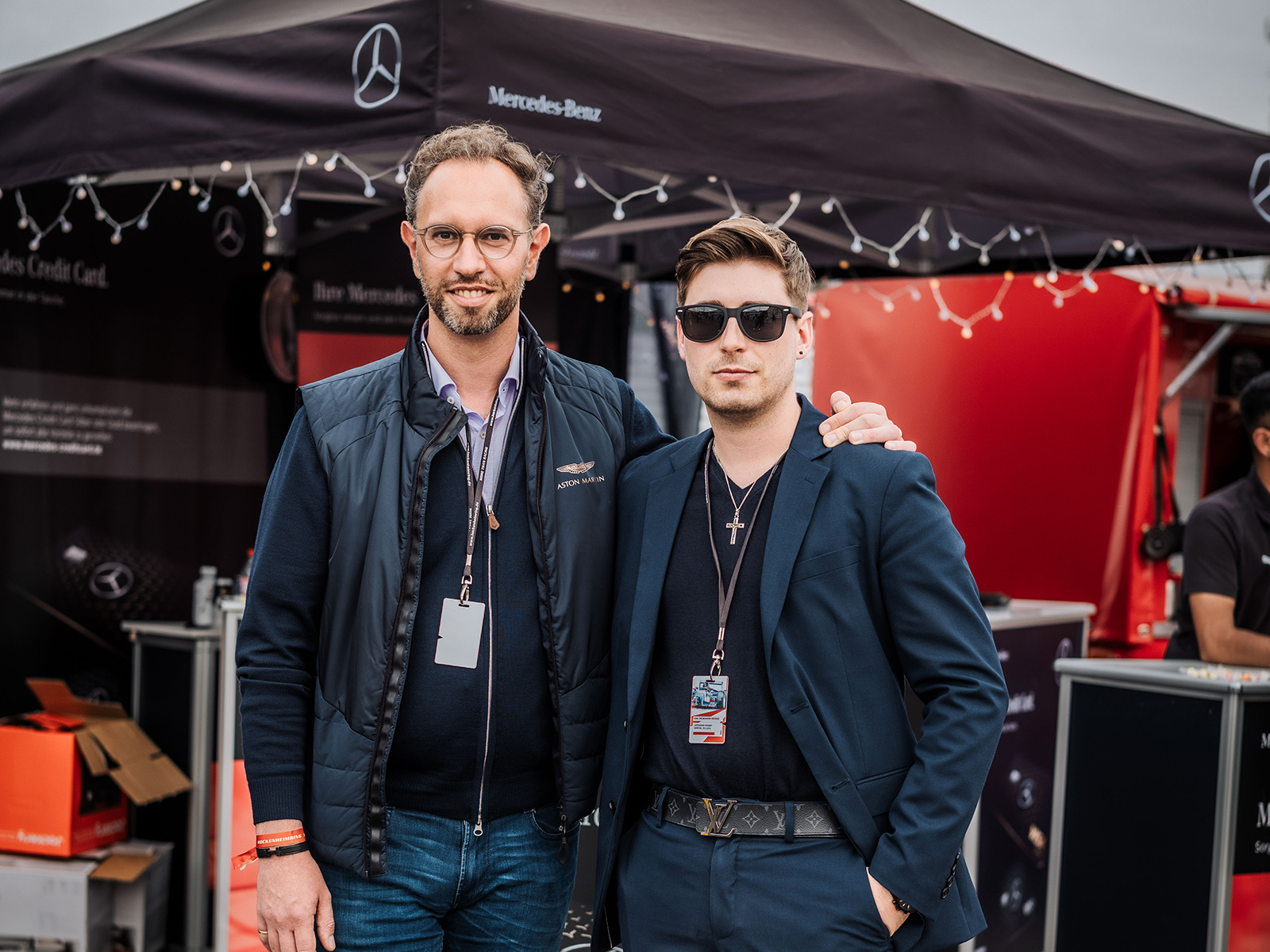 Zwei Männer posieren gemeinsam im Fahrerlager bei einer Motorsportveranstaltung am Hockenheimring.