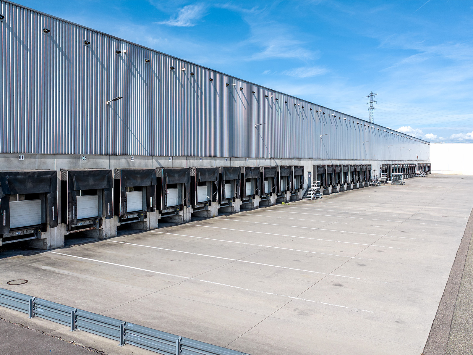 Außenansicht des Logistiklagers in Bietigheim mit einer langen Reihe von Laderampen für Lkw.