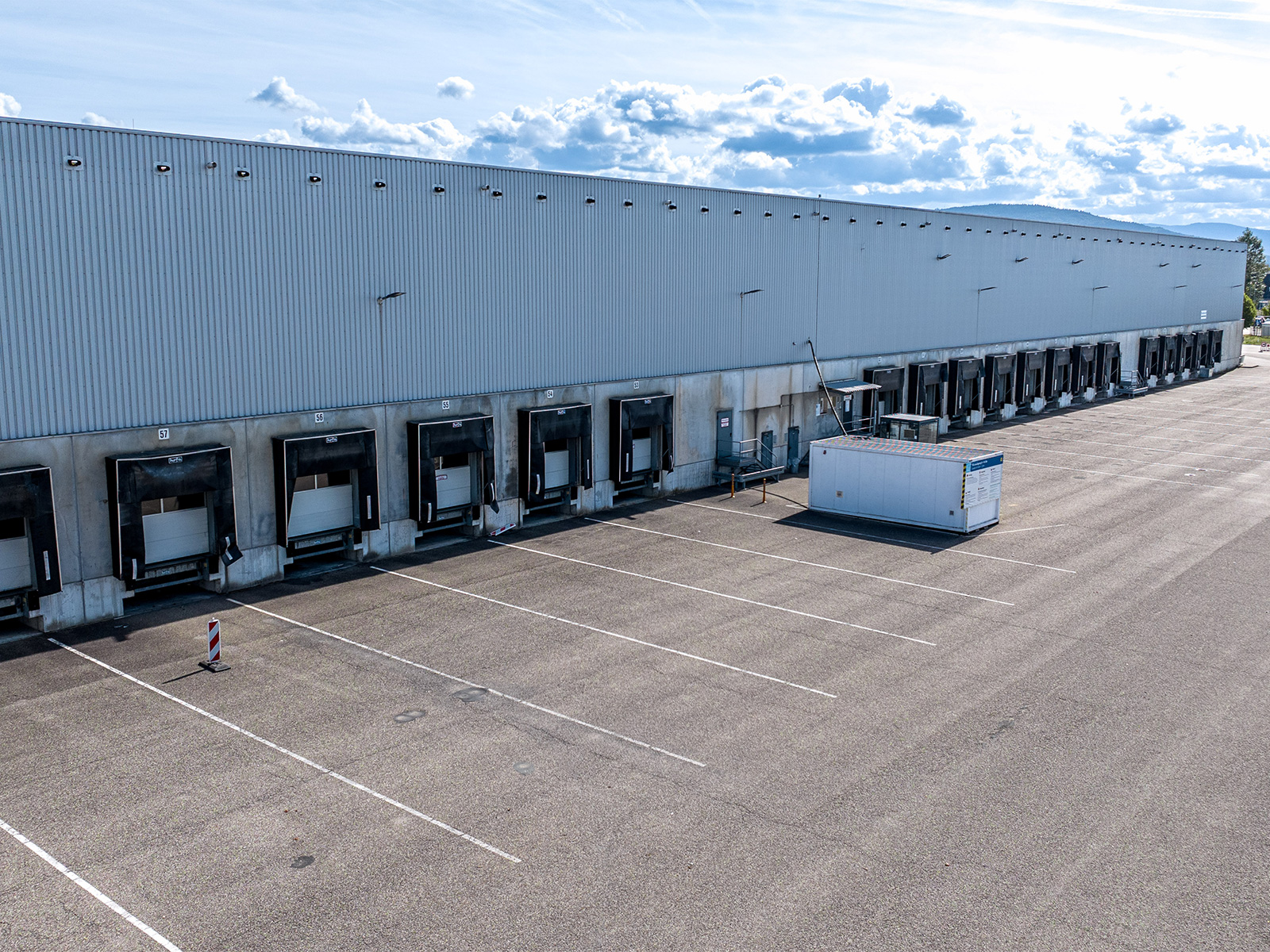 Außenansicht des Logistiklagers in Bietigheim mit Bürogebäude, großflächiger Lagerhalle und zahlreichen Laderampen.