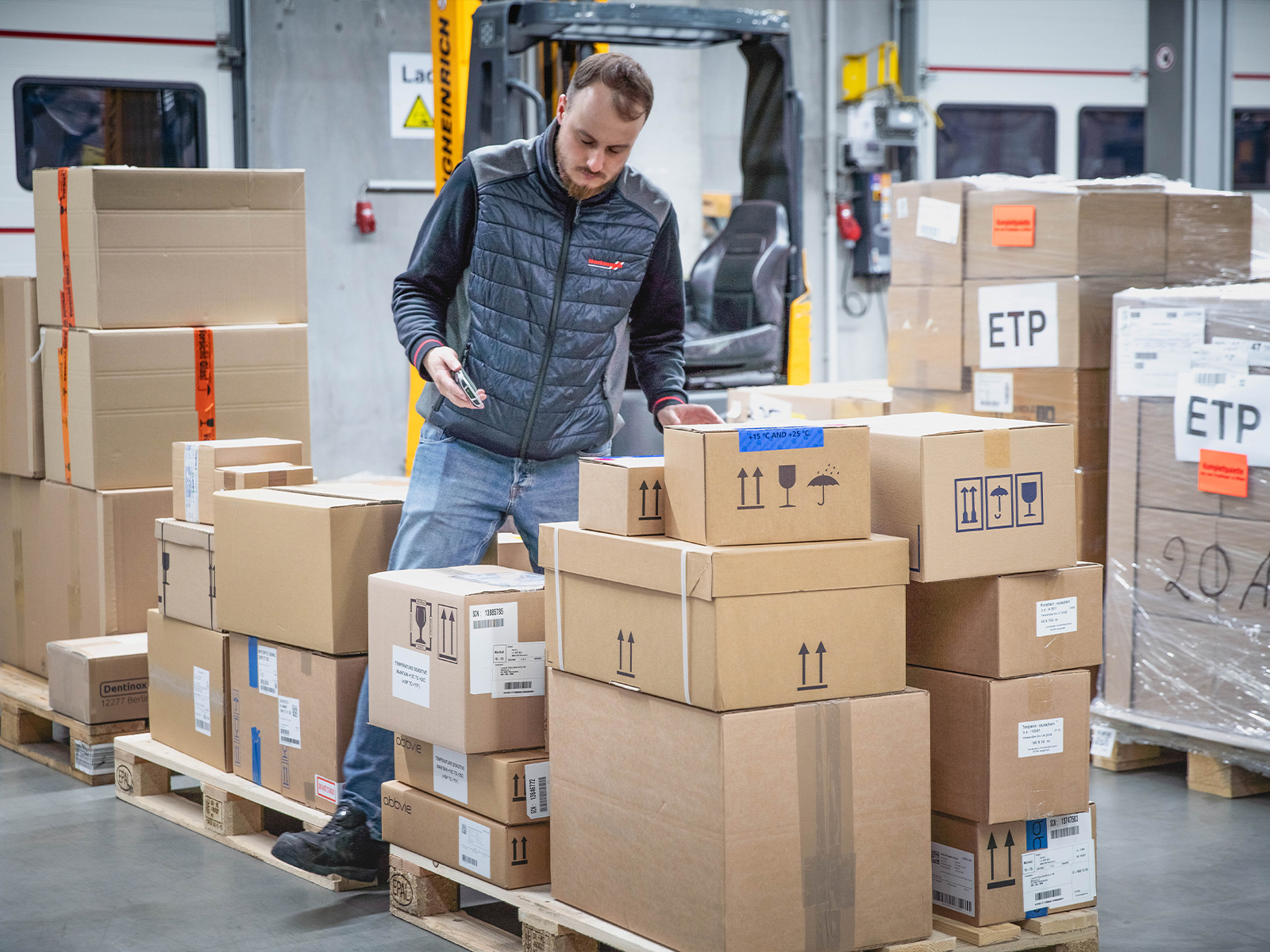 Hartmann-Mitarbeiter kontrolliert und erfasst Versandkartons auf Paletten in einer Logistikhalle für die Pharmalogistik.