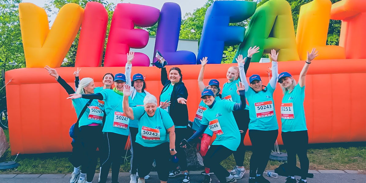 Hartmann-Team beim B2Run Firmenlauf vor dem VIELFALT-Schriftzug
